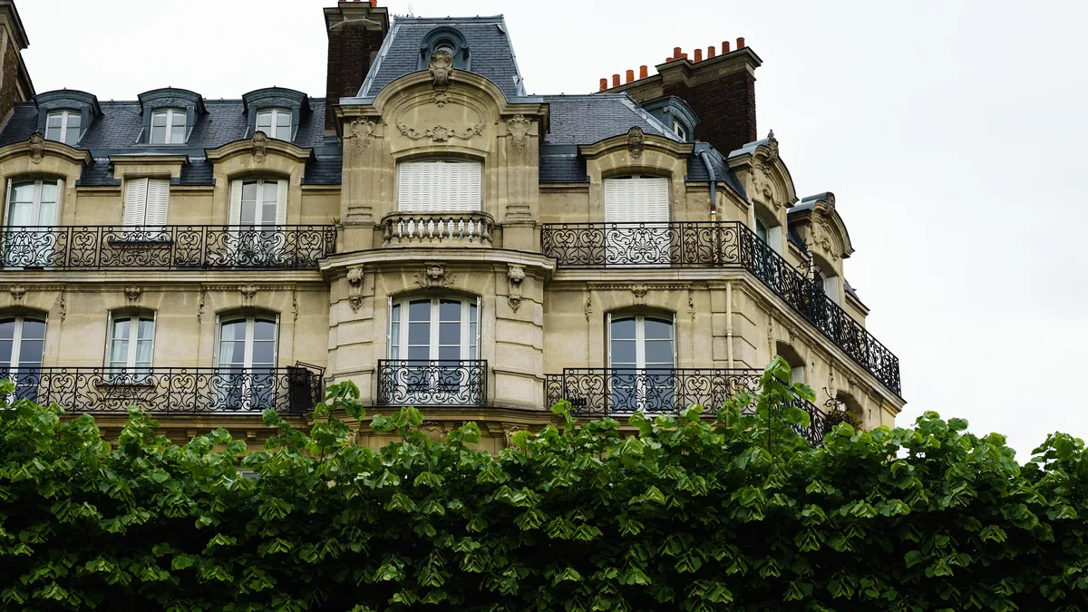 Wrought-iron balconies on a Paris Haussmann building, the kind of apartment transferred by a notarial acte authentique