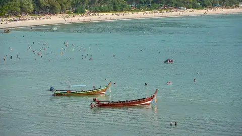 Kata Beach with long-tail boats and umbrellas — the family-tourism bay shared by the Karon and Kata condo market
