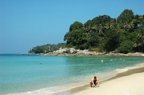 Surin Beach with villa-covered headland — the boutique premium tier of the Phuket condo market