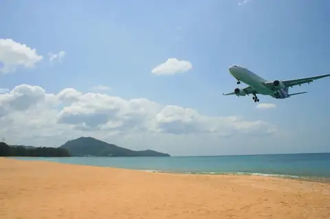 A jet on final approach over Mai Khao Beach — the Thalang airport corridor where Phuket's new mid-market condo supply lands